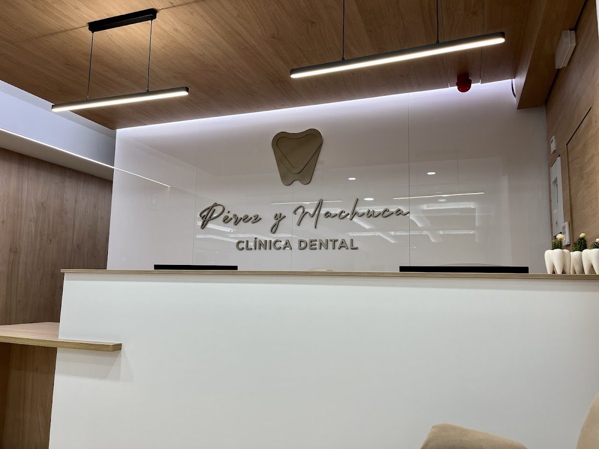 Modern reception area of CLÍNICA DENTAL PÉREZ Y MACHUCA with wooden accents and a dental logo.