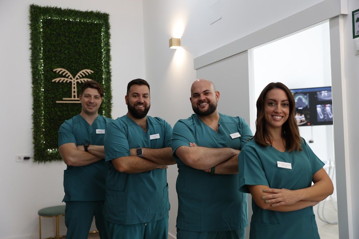 Clínica Dental Playamar staff in teal scrubs, smiling and posing in a modern dental office.