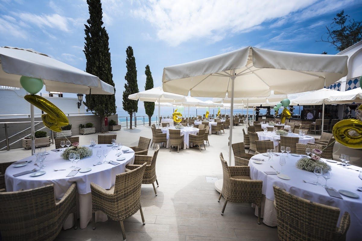 Outdoor dining area at Cochran's Terrace with tables, umbrellas, and a coastal view.