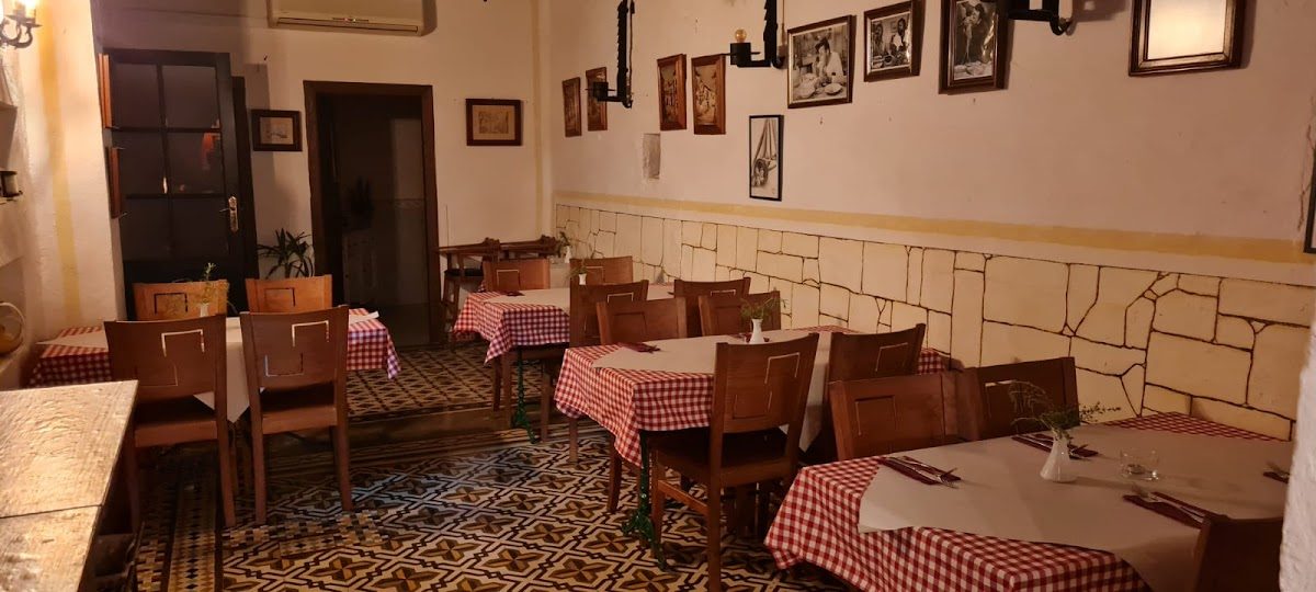 Interior of Colosseo restaurant featuring checkered tablecloths and decorative wall art.