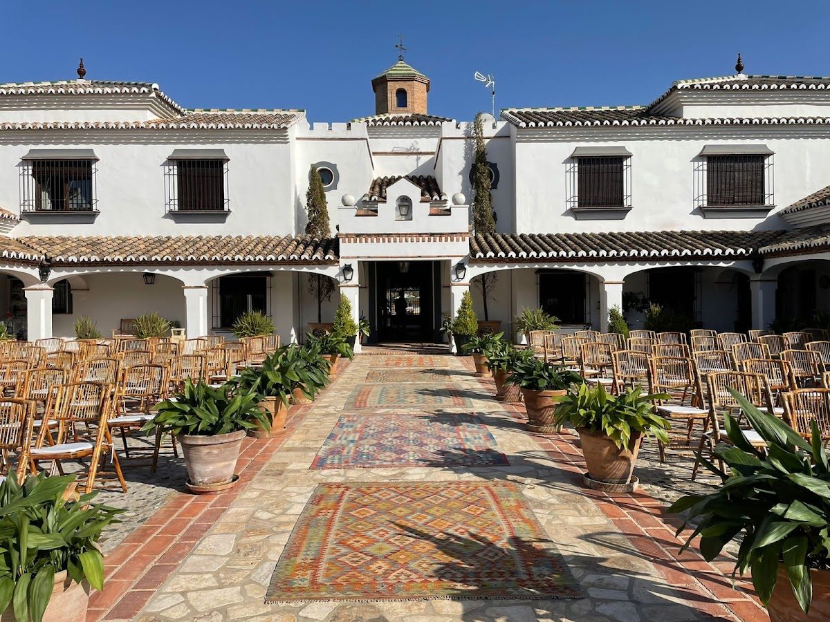 Cortijo Curiel cuenta con un precioso patio con asientos, plantas y alfombras decorativas, perfecto para eventos.