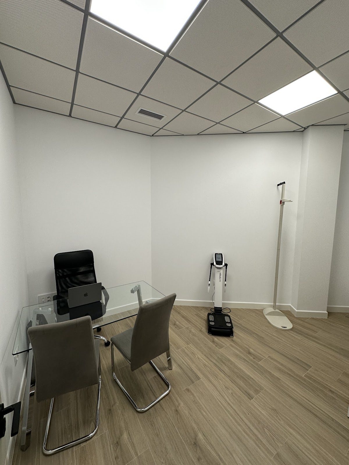Una moderna sala de consulta equipada con una mesa de cristal, sillas y material para la evaluación de la salud.