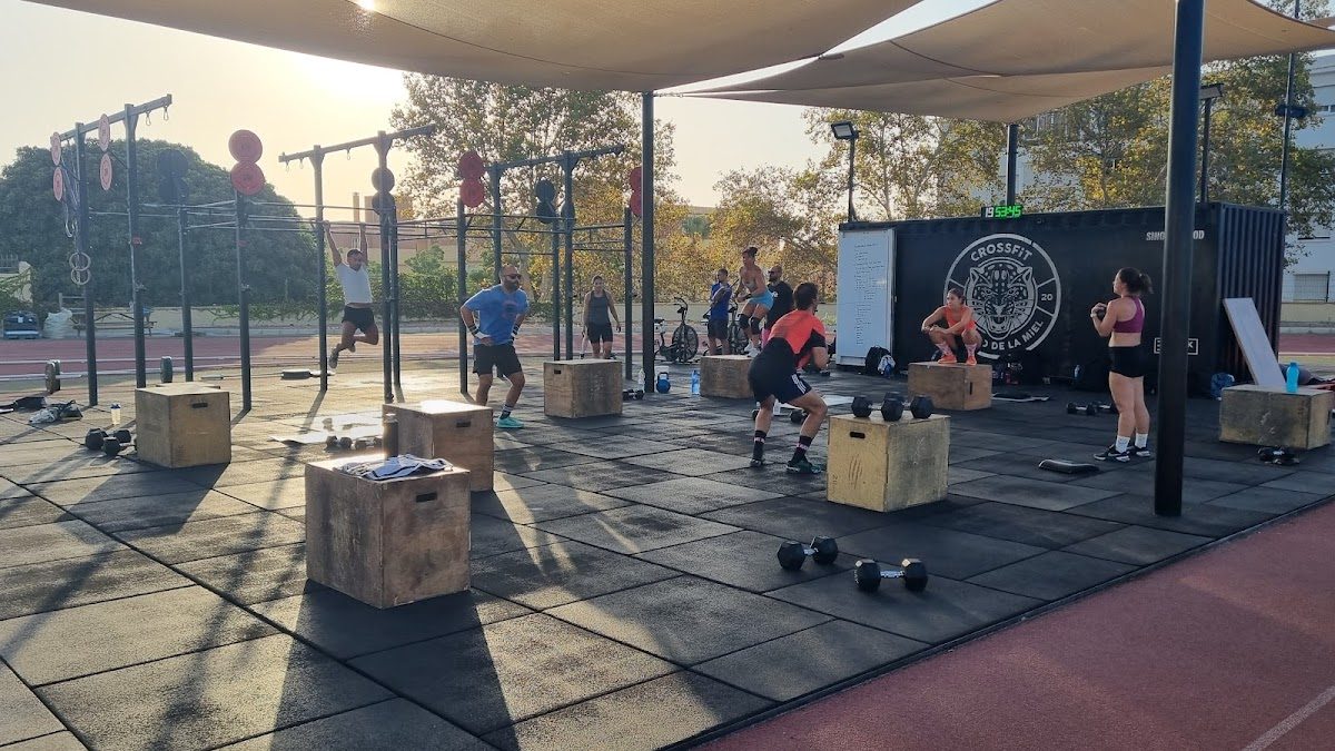 Outdoor CrossFit training session with athletes using weights and equipment on a rubberized floor at CrossFit Arroyo de la Miel.