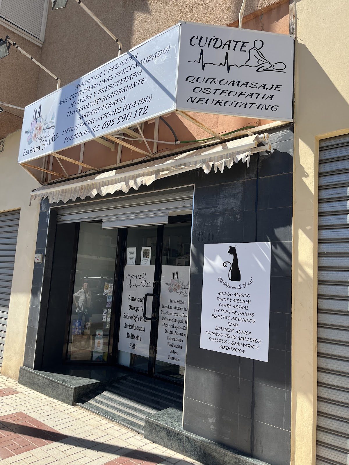Cuidate quiromasaje y osteopatia storefront with signage and a black cat silhouette on the window.