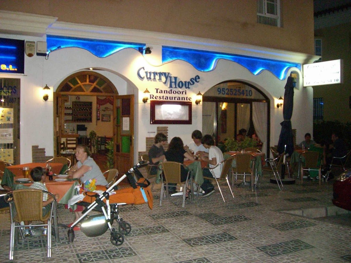Curry House Nerja features outdoor seating with diners enjoying meals under blue lighting.