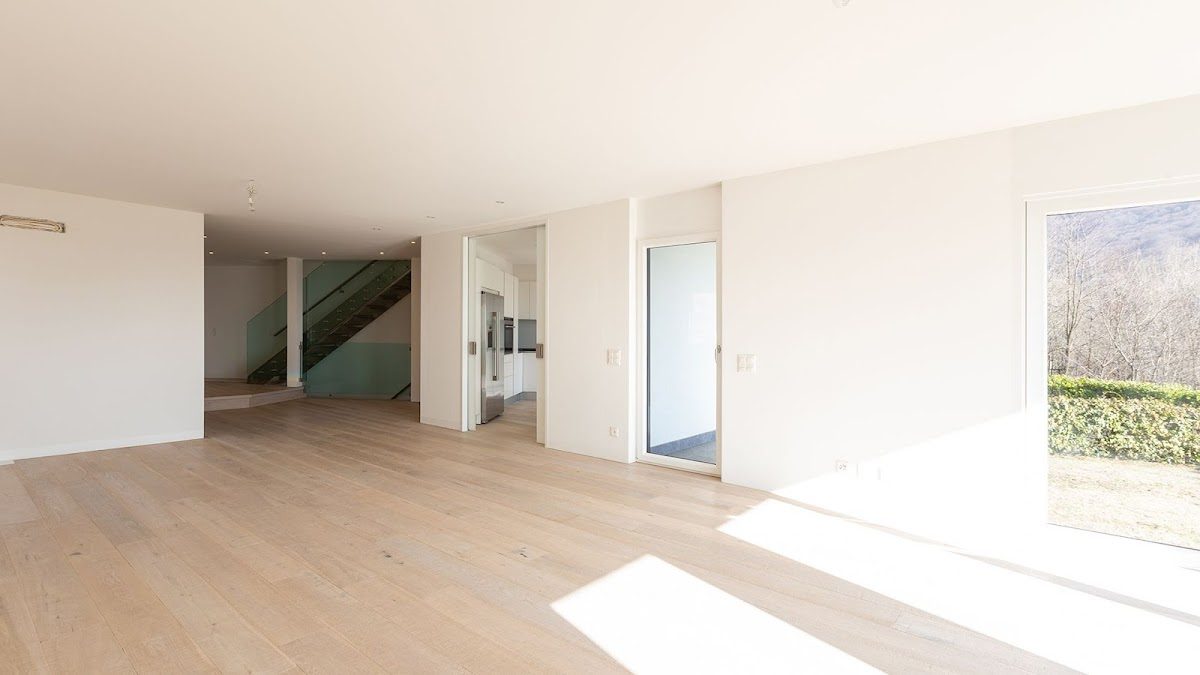 Interiores amplios y modernos con suelos de madera clara y grandes ventanales en D&V Reformas Torremolinos.