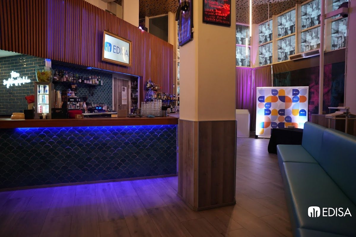 Vista interior de Day Off Events Málaga, que incluye una zona de bar con asientos e iluminación colorida.