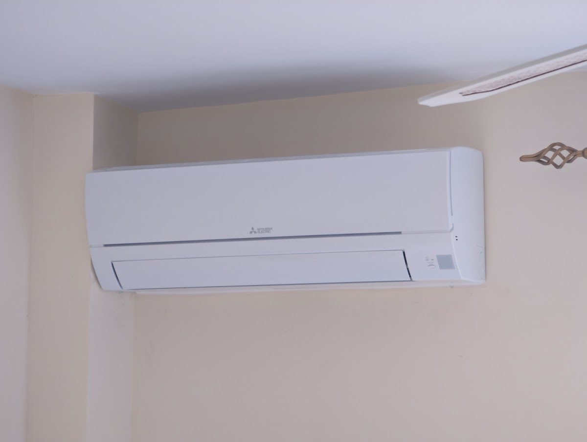 Un aparato de aire acondicionado montado en la pared de una habitación de color claro.