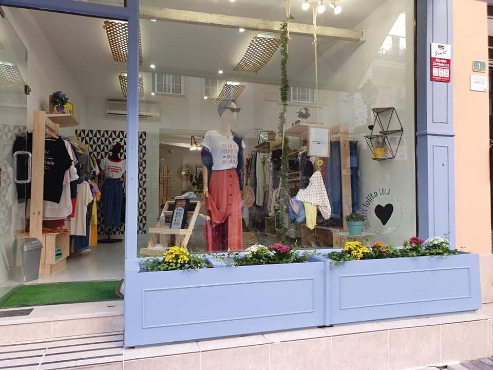 The storefront of Dolores Lolita Lola features colorful clothing displays and flower planters.