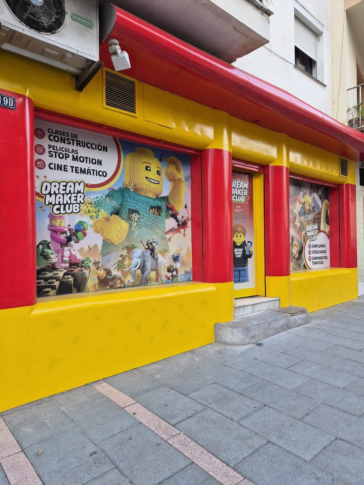 Exterior colorido del Dream Maker Club con carteles promocionales de clases y actividades relacionadas con Lego y la animación stop motion.