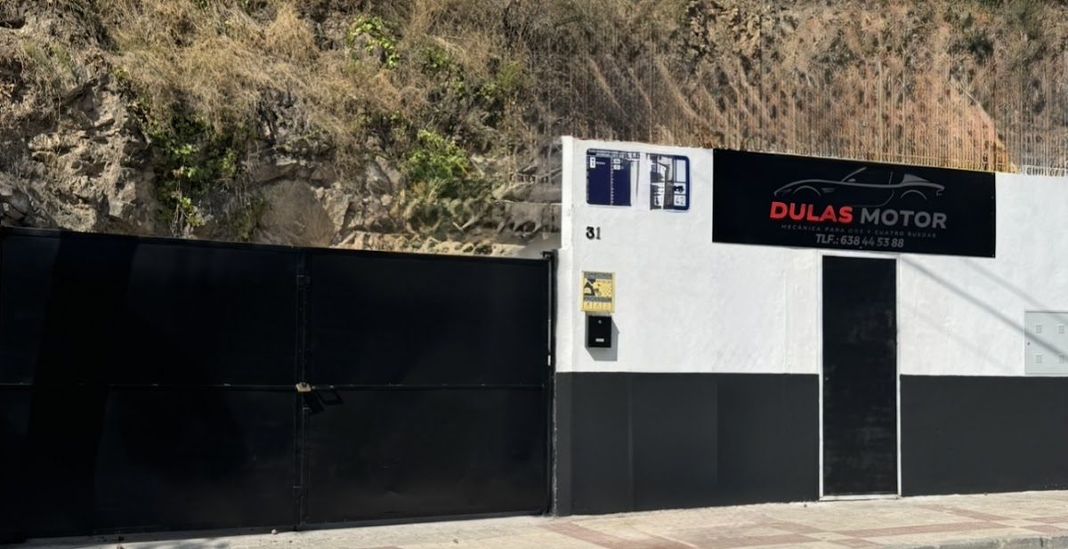 Dulas Motor presenta un exterior moderno con una puerta negra y señalización en una ladera de Málaga.
