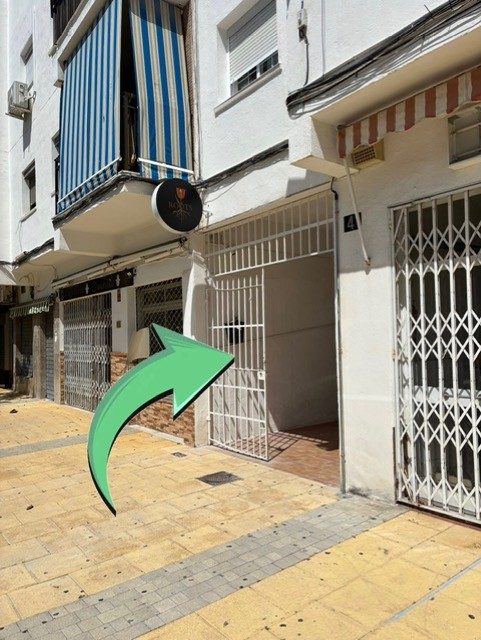 The entrance to Dutch Roots Social Club, featuring a sign and a gated doorway on a street in Estepona.