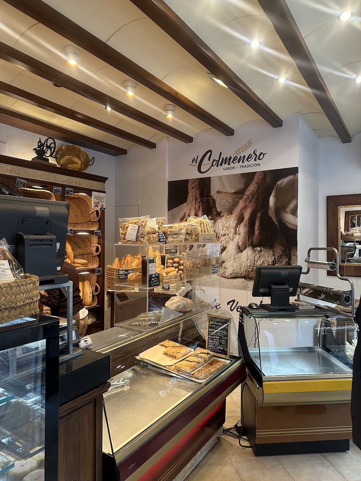 Interior of El Colmenero de Alhaurín showcasing a display of baked goods and a cash register.