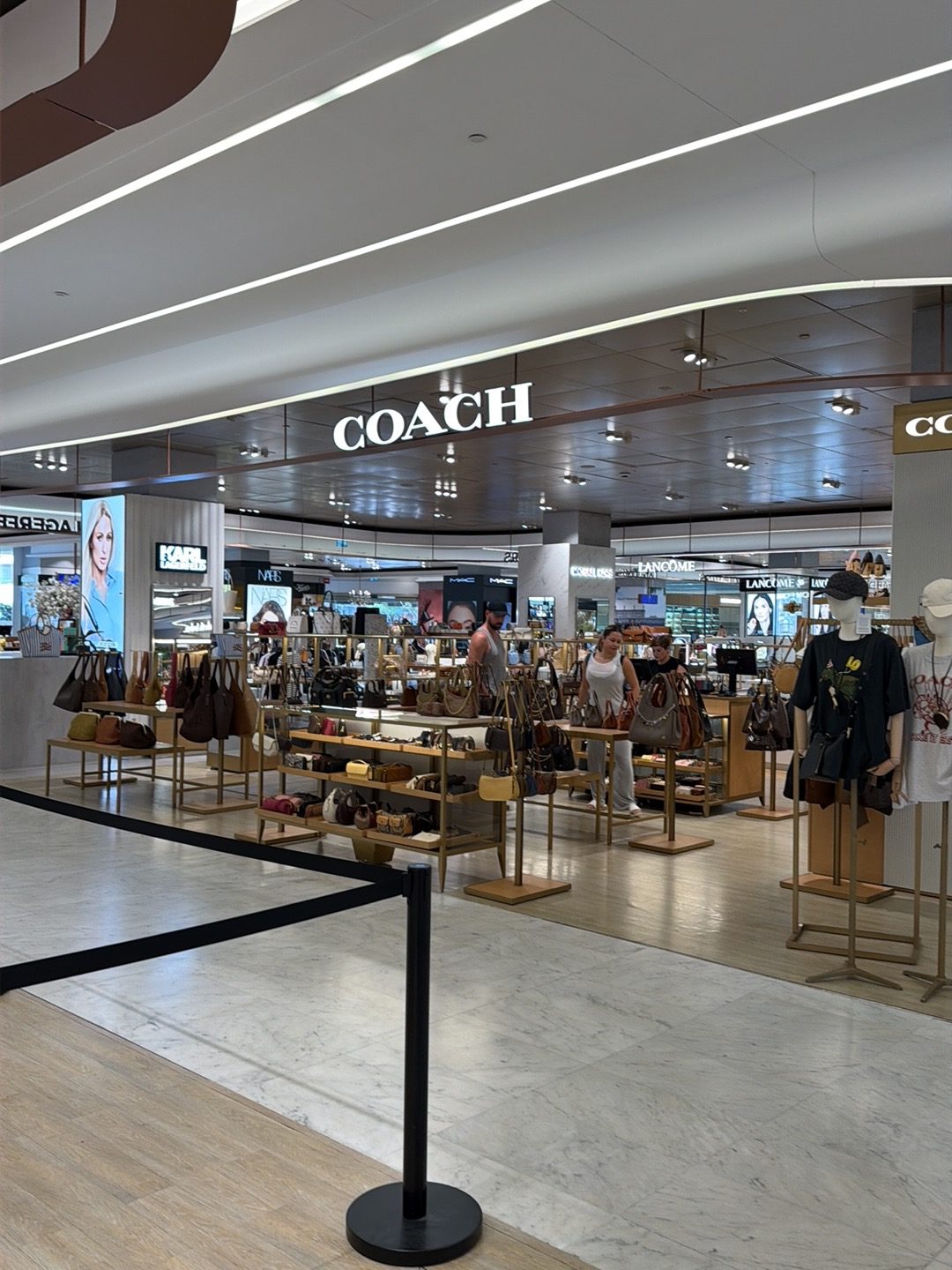Vista interior de la tienda Coach en El Corte Inglés Puerto Banús, donde se exhiben bolsos y accesorios.