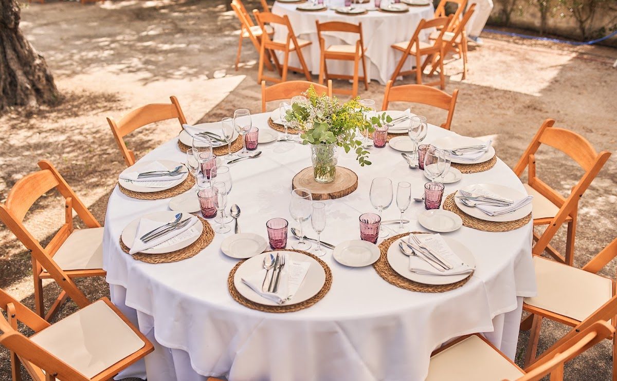 Elegant outdoor dining setup with round tables, white tablecloths, and floral centerpieces at El Cuchareo.
