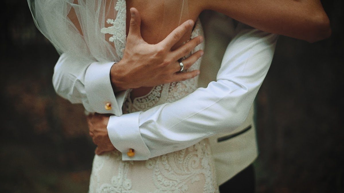 Primer plano de una pareja abrazándose, mostrando detalles del vestido de novia y del traje del novio.