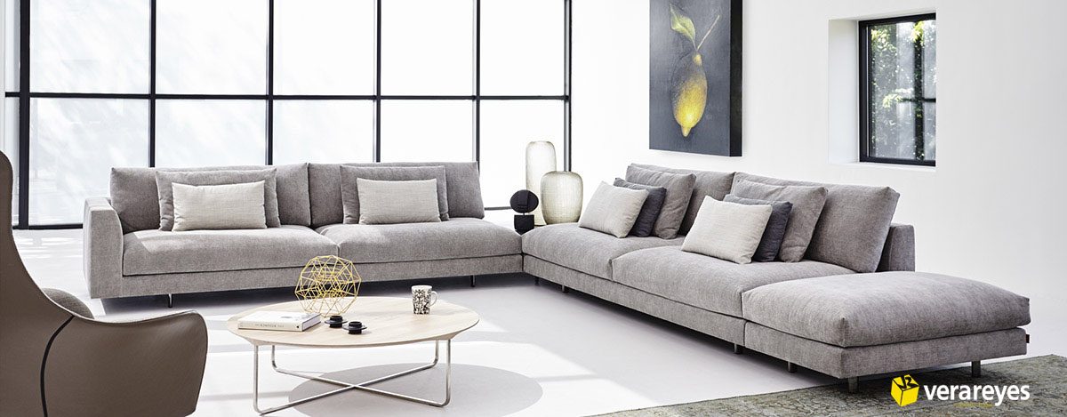Sofás modernos de color gris y una elegante mesa de centro en una luminosa y minimalista sala de exposición de Electro Muebles Verareyes.