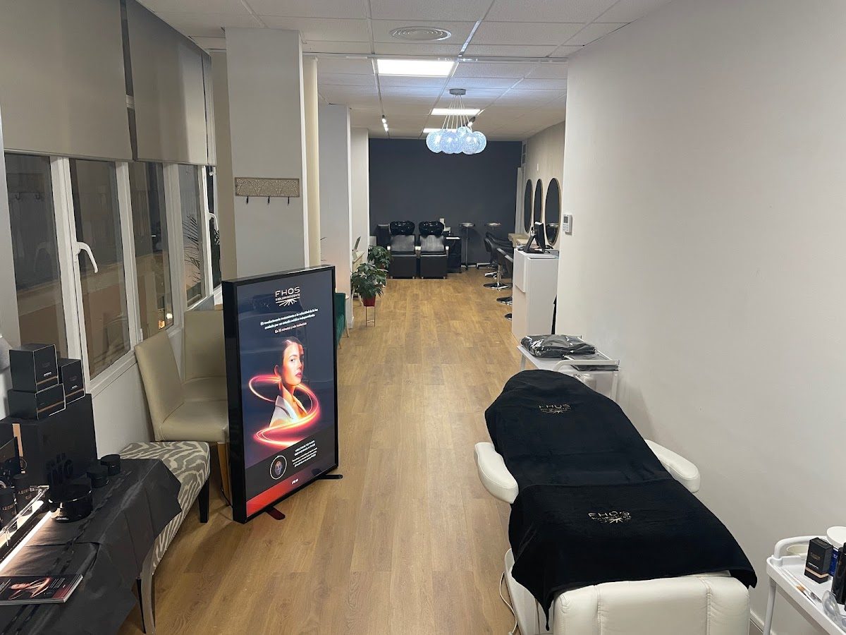 Interior del Elite Beauty Center con camillas de tratamiento, sillas y un letrero informativo.