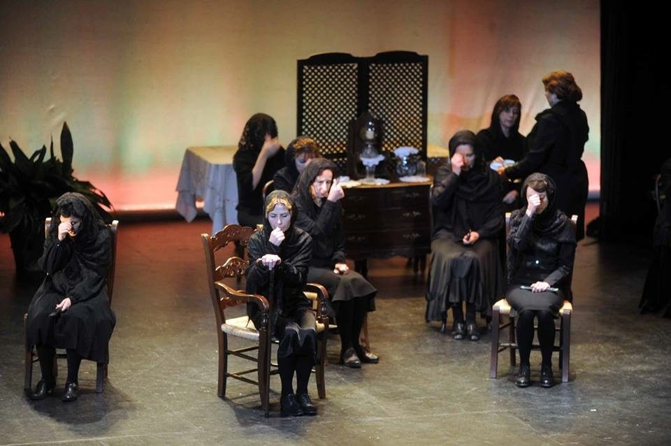 A theatrical performance featuring actors in black costumes on stage at Escuela de Teatro Proyecto Platea.