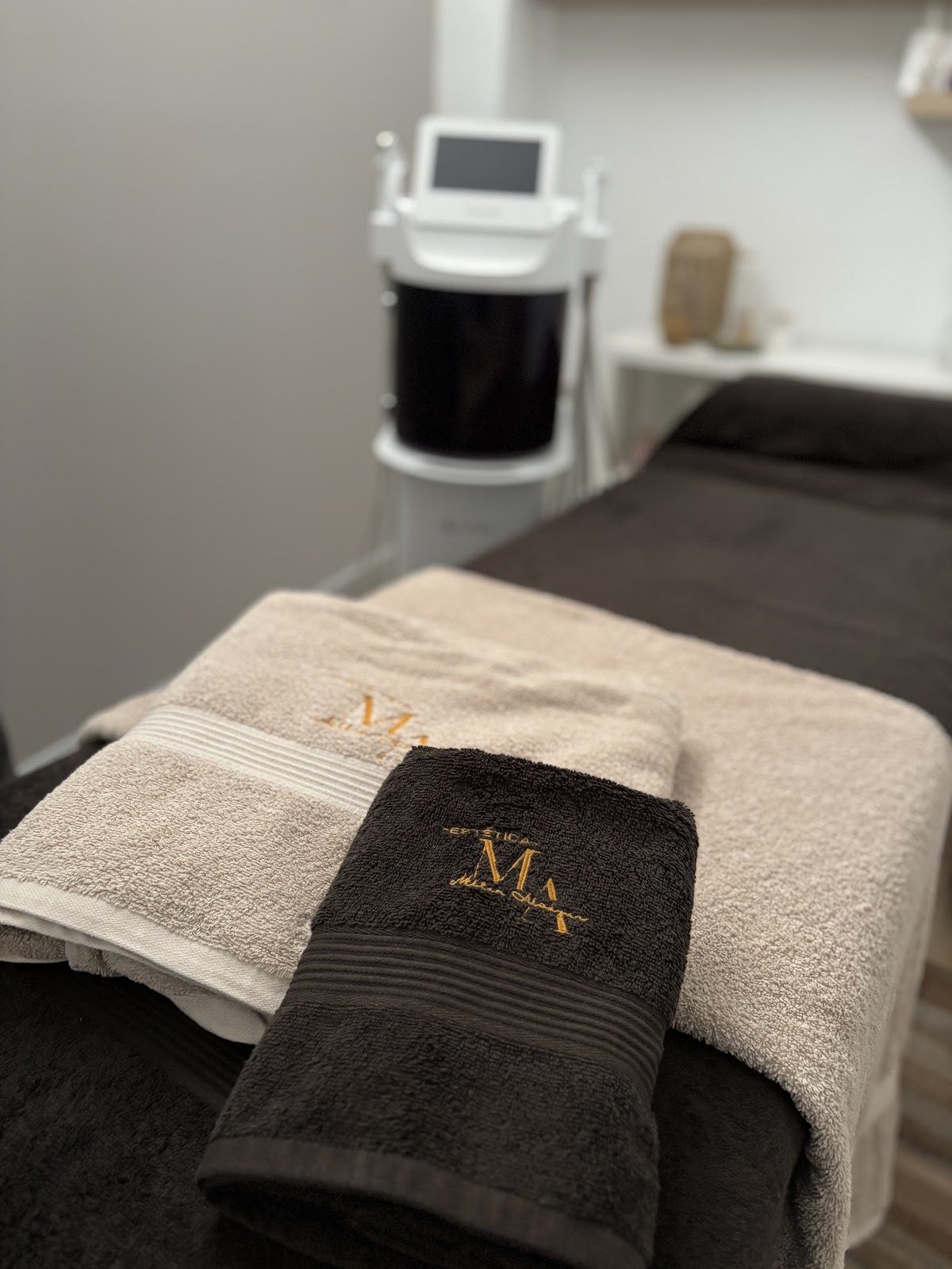 Treatment room at Estética Millan Alcazar featuring towels and a skincare machine.