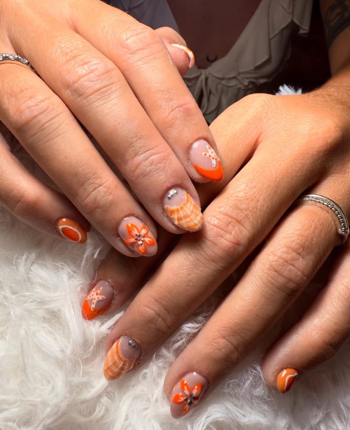 Colorful nail art featuring orange designs and embellishments at Estudio Nails&Beauty Rosmery Parra.