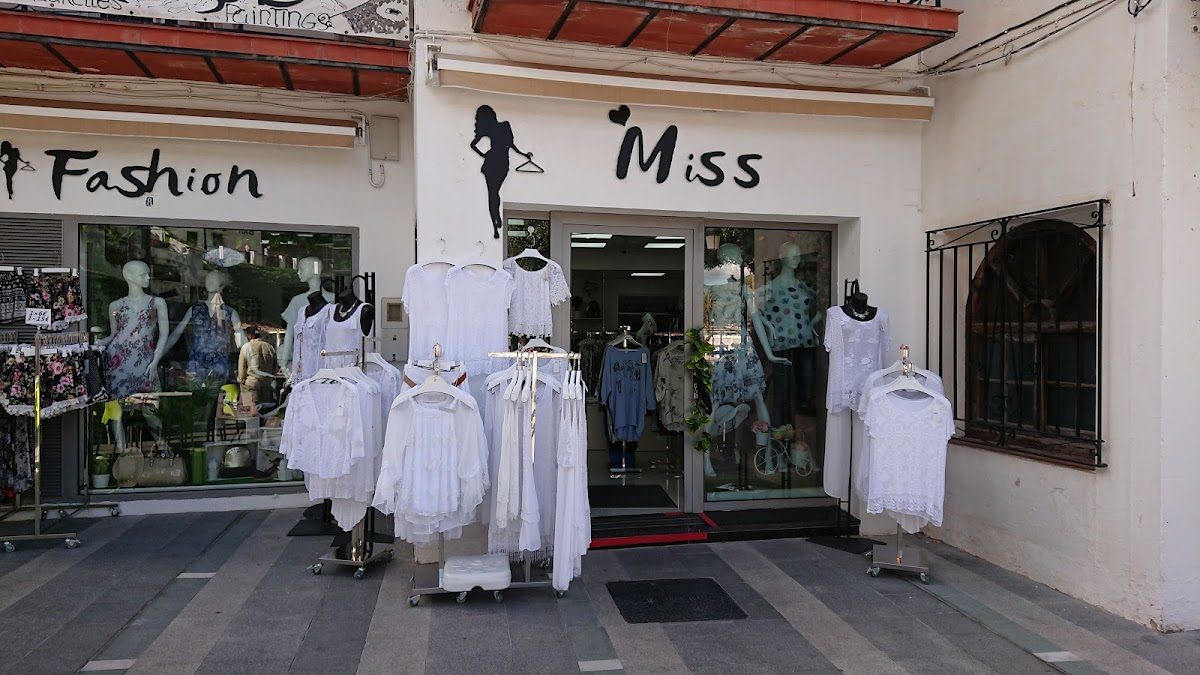 The storefront of Fashion Miss features white clothing displayed on mannequins and hangers.