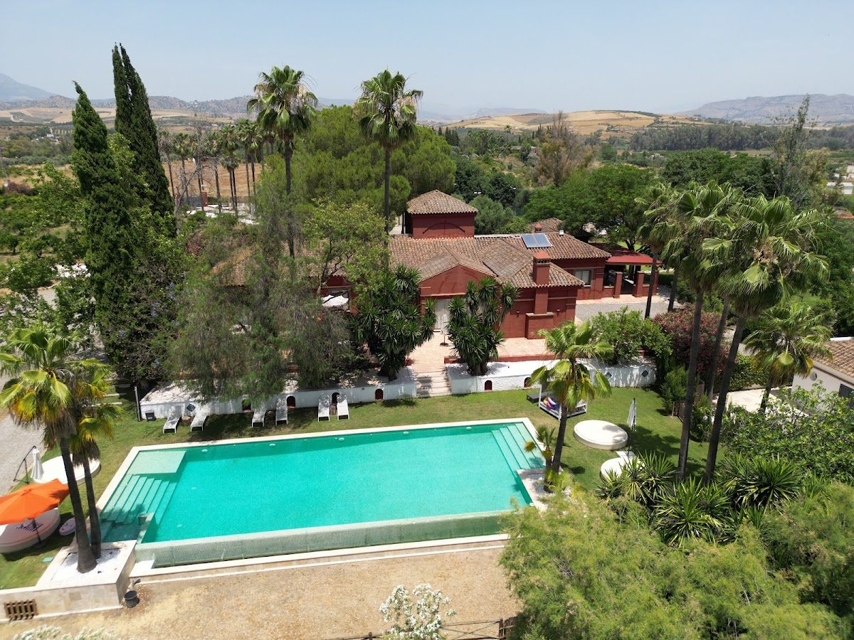 Finca La Familia Naranja cuenta con una gran piscina al aire libre rodeada de palmeras y un encantador edificio con techo rojo.