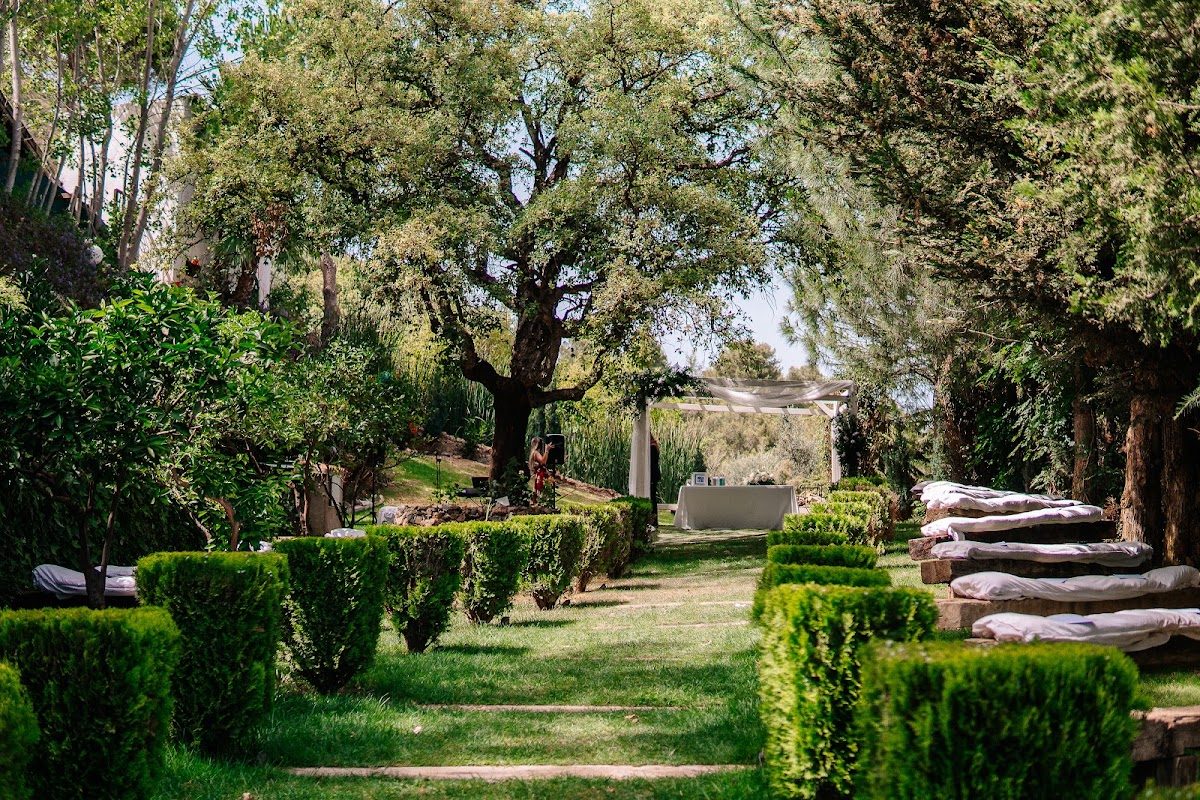 Lush garden pathway with neatly trimmed hedges and seating areas at Finca Villa Palma in Ojén.