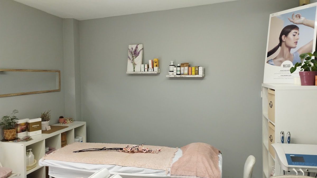 Una tranquila sala de tratamientos de belleza con camilla de masaje, estantes con productos y una decoración acogedora en Flor La Vie en Rose.