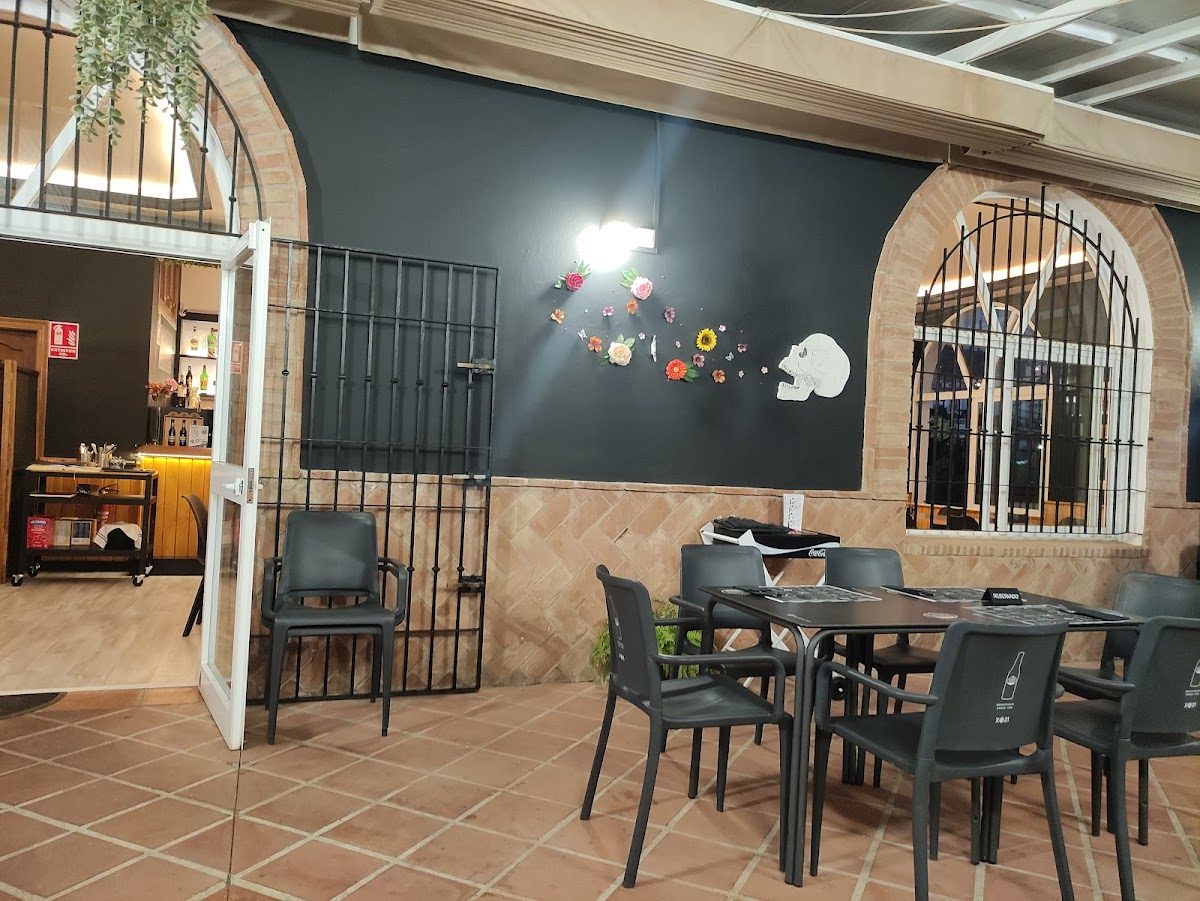 Outdoor seating area with black walls, decorative flowers, and an entrance to the interior of Food Karma Gastro.