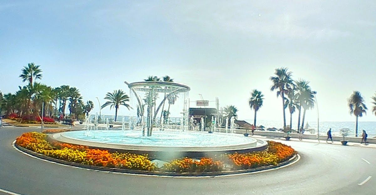 Una fuente decorativa rodeada de coloridas flores y palmeras cerca de la costa en Estepona.