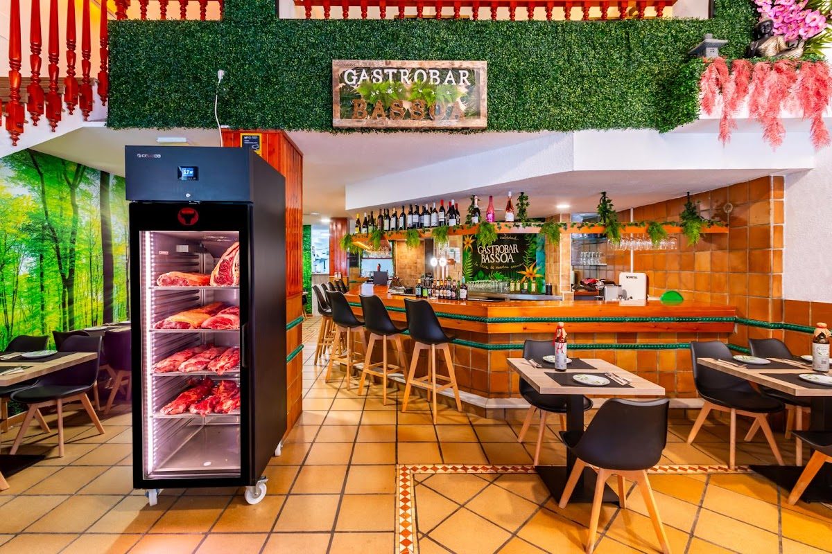 Interior of Gastrobar Bassoa featuring a bar, seating area, and a meat display fridge.