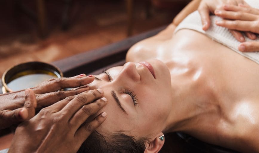 A woman receives a facial treatment at Gemburu Wellness, showcasing a serene spa environment.