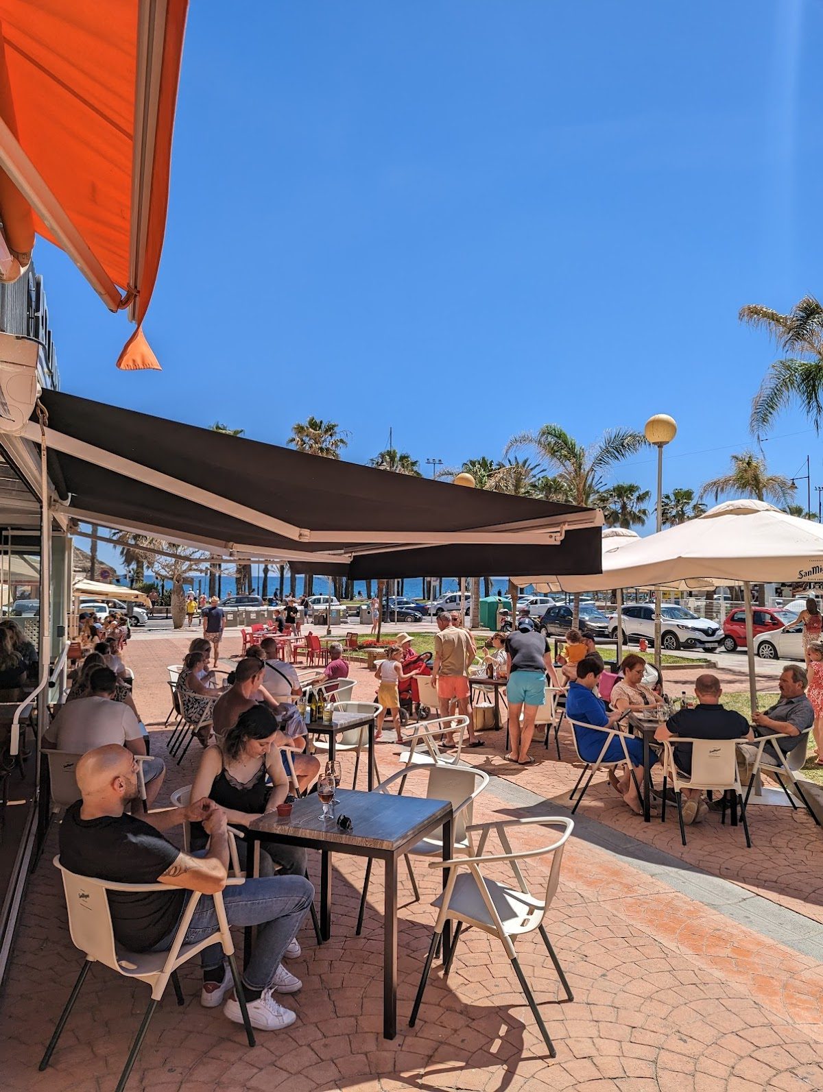 Terraza al aire libre del restaurante Get Lucky Brunch & Bar, donde los clientes disfrutan de sus comidas bajo sombrillas.