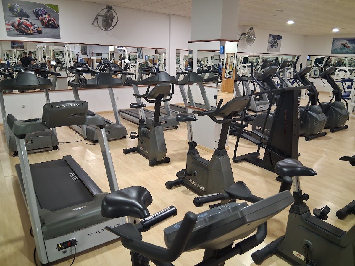 Vista interior del Gimnasio Olimpus, donde se muestran diversos equipos y máquinas de fitness.