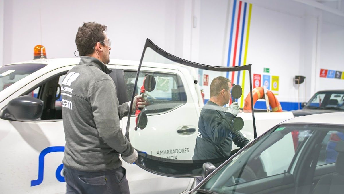 A technician at Glassdrive Nerja is installing a car windshield in a workshop.