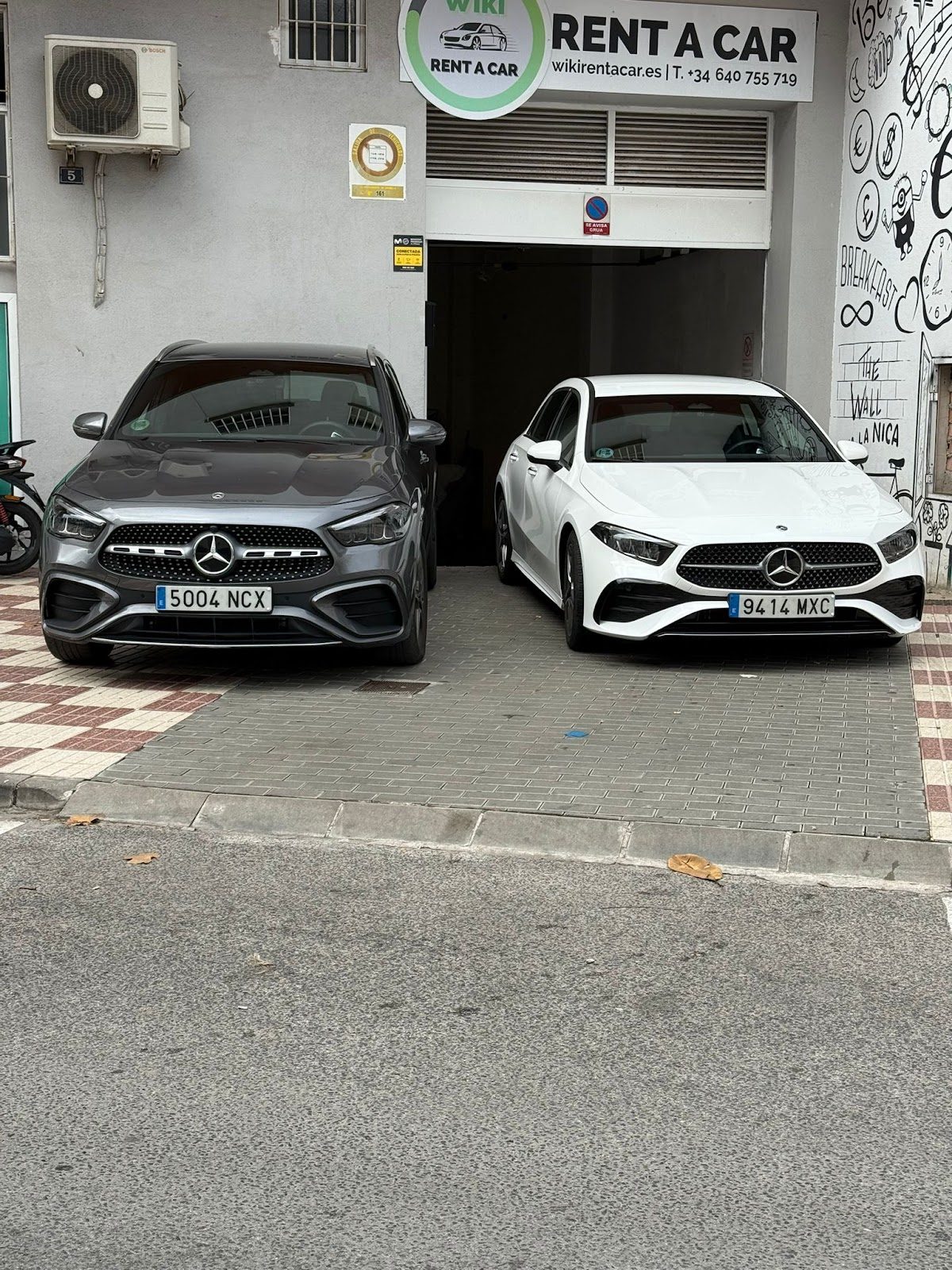 Dos coches Mercedes aparcados frente a Go Rent A Car Marbella, con una oficina de alquiler de coches visible al fondo.
