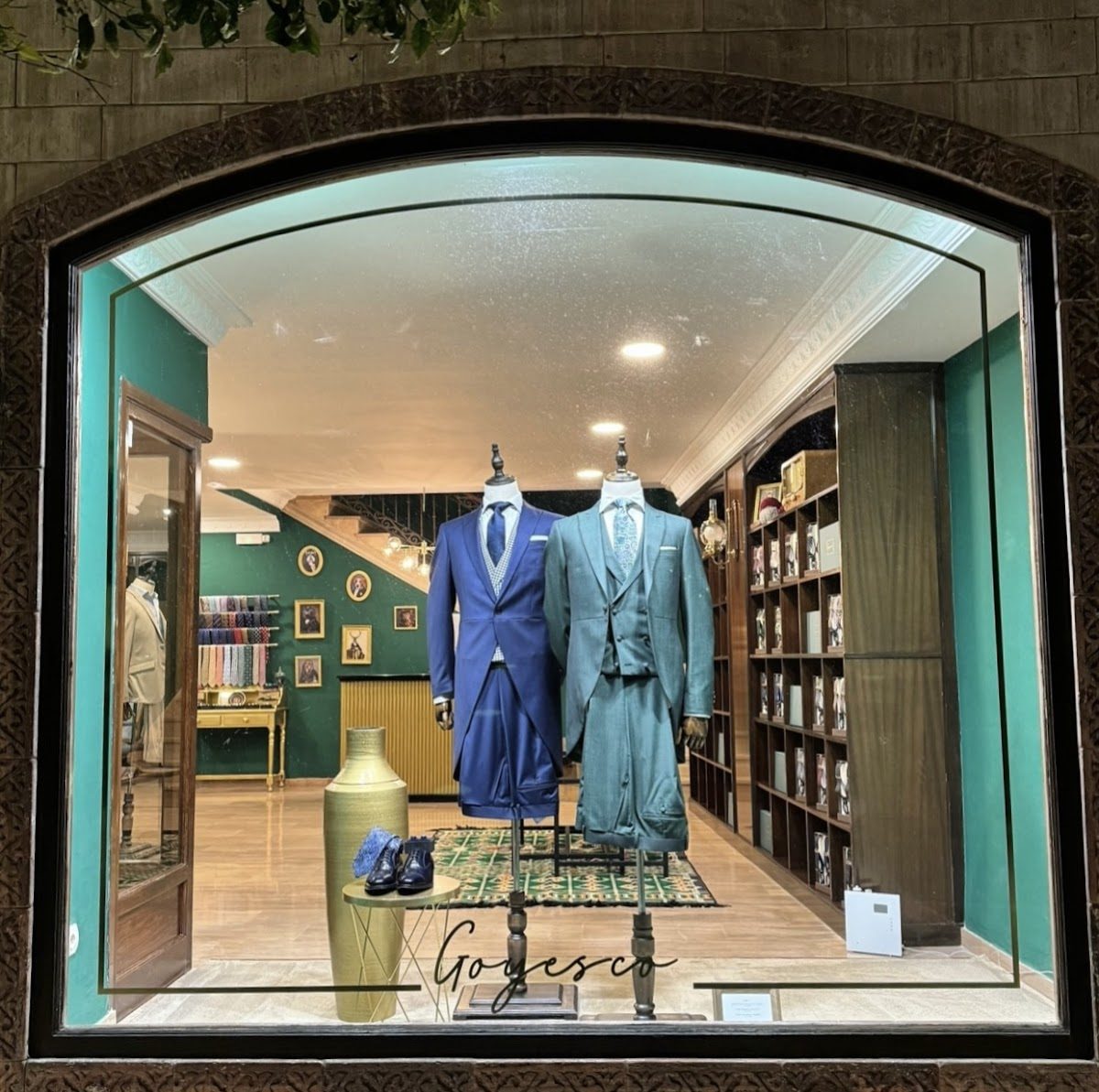 Goyesco showcases elegant suits in a stylish store window with a green interior.