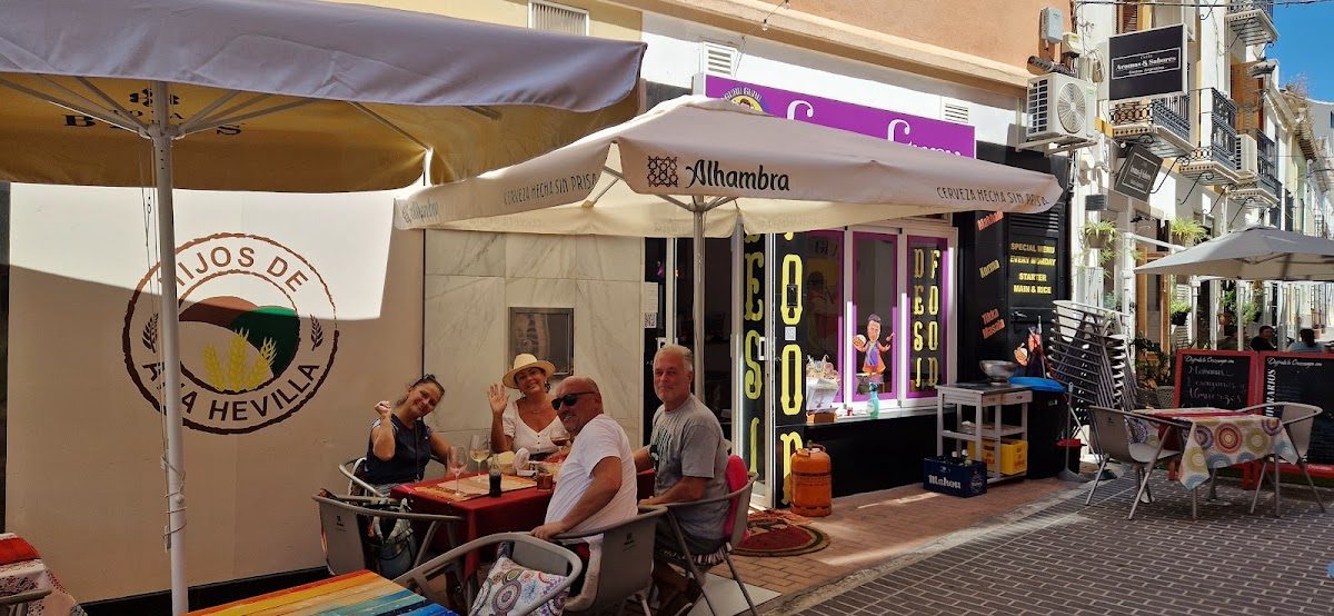 Outdoor seating area with colorful tables and umbrellas at GURU GURU DESI FOOD in Coín, Málaga.