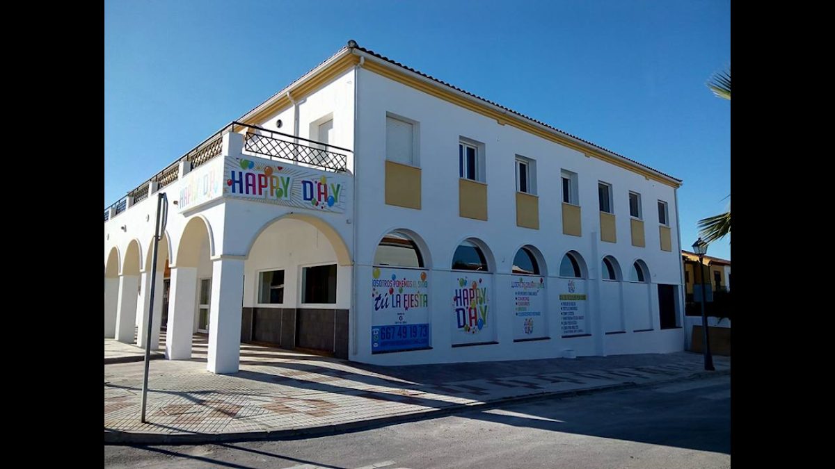 The exterior of HAPPY DAY CELEBRACIONES features a white building with colorful signage and large arched windows.