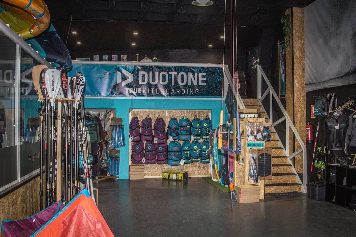 Interior de HoeNalu con equipo de kitesurf, mochilas y una escalera en un entorno de tienda moderno.