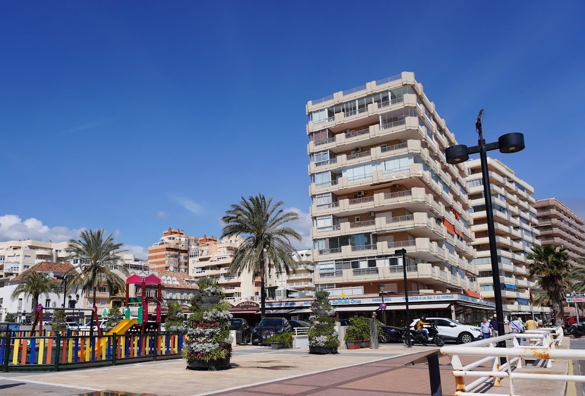 Hostal Costabella is located in a multi-story building near palm trees and a playground in Fuengirola.
