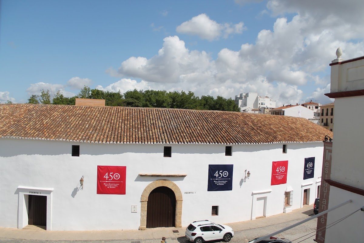 El Hotel Acinipo presenta un edificio blanco tradicional con techo de tejas y coloridas pancartas.