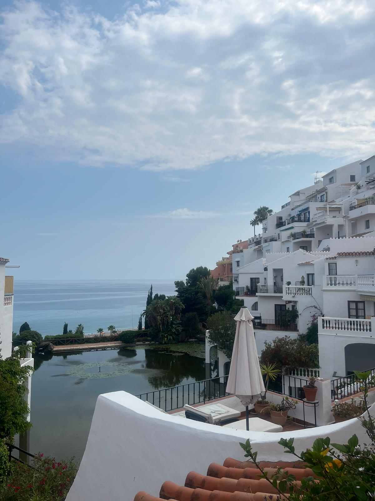 Hotel Bajamar Ancladero Playa features white buildings overlooking a serene pond and the sea.