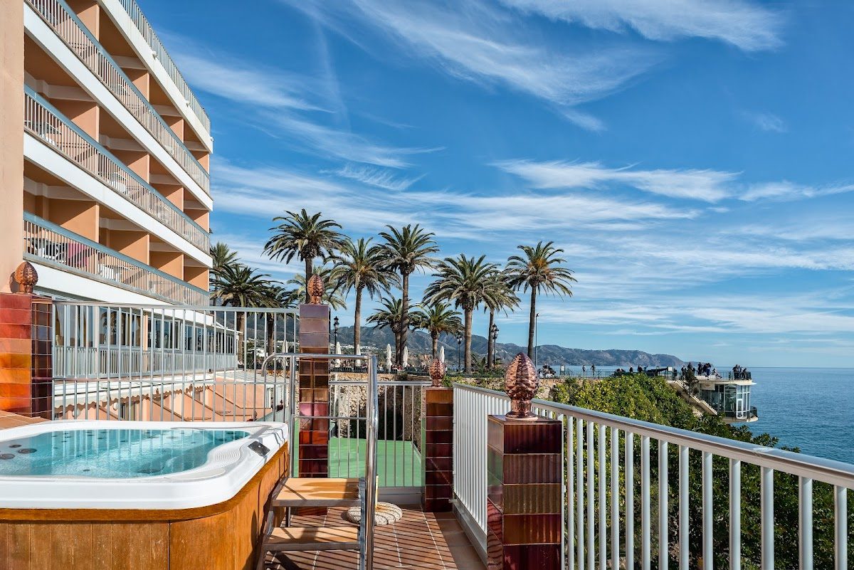 Hotel Balcón de Europa features a terrace with a jacuzzi and views of palm trees and the sea.