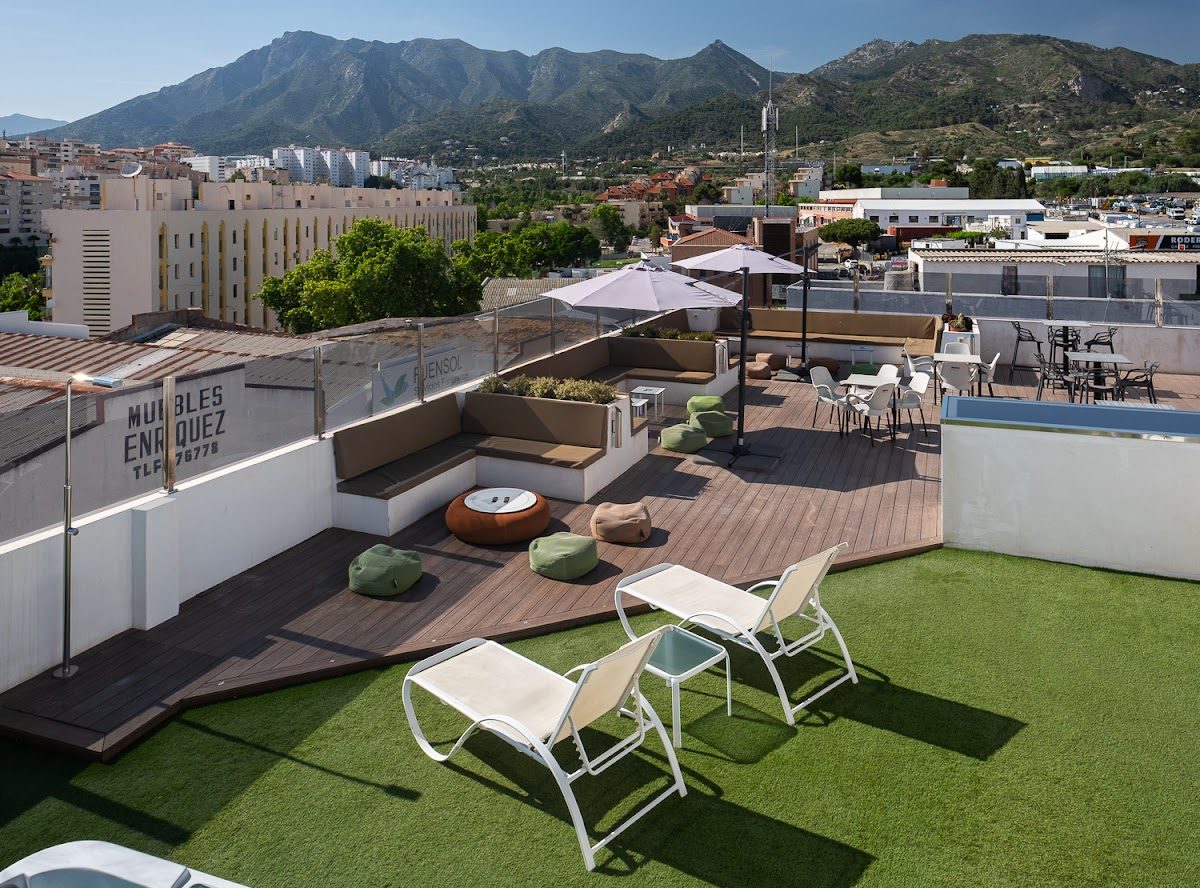 Rooftop terrace at Hotel Daos featuring lounge chairs, green grass, and mountain views in Marbella.