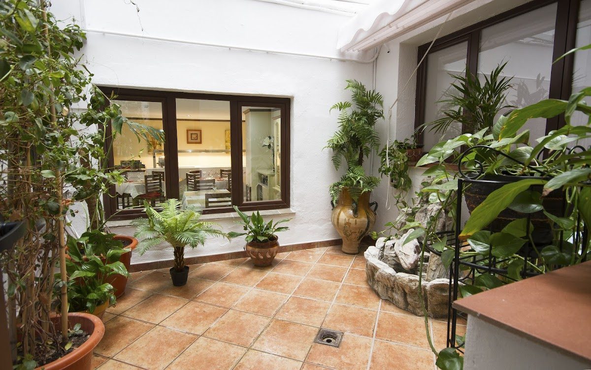 Patio interior del Hotel El Tajo & SPA con plantas, una fuente y suelo de baldosas.