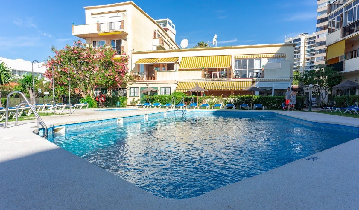 Hotel Los Jazmines features a swimming pool surrounded by sun loungers and lush greenery.