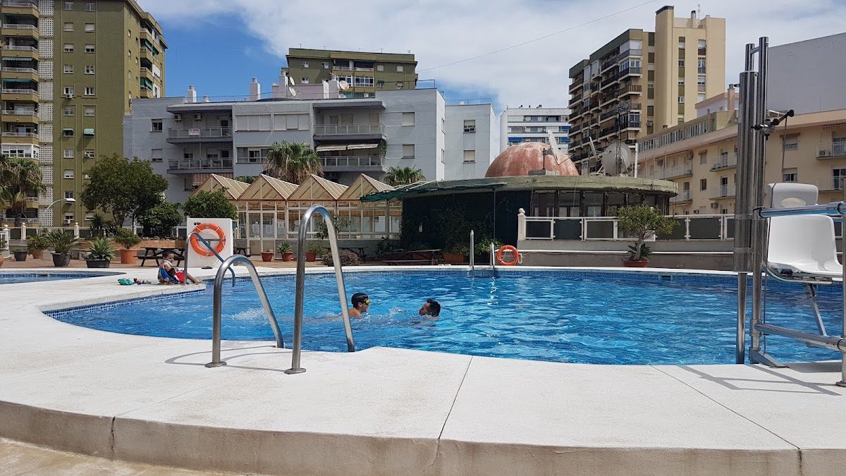 The image shows a swimming pool area at Hotel Manantiales with children playing in the water.
