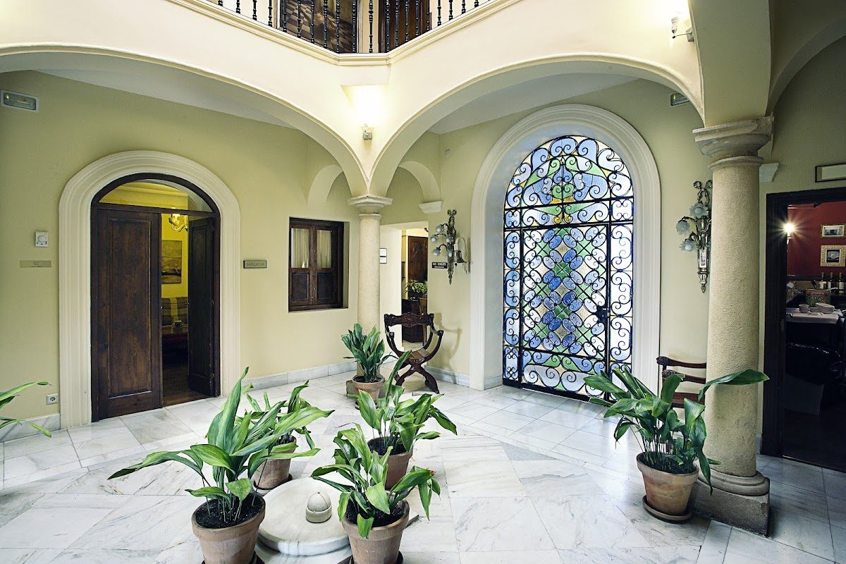 Elegante vestíbulo del Hotel Montelirio con suelos de mármol, puertas arqueadas y plantas decorativas.